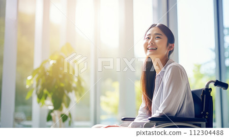 Happy, smiling young Asian girl student in a wheelchair in the foyer of an educational institution. 112304488