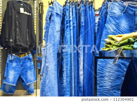 Row of hanged blue jeans in a shop. Clothes store. Shopping in fashion mall. Garments on hangers 112304901