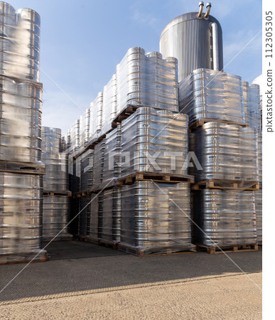 Large amount of aluminium beer kegs stacked on each other with euro palettes and wrapped around with vinyl foil. 112305305