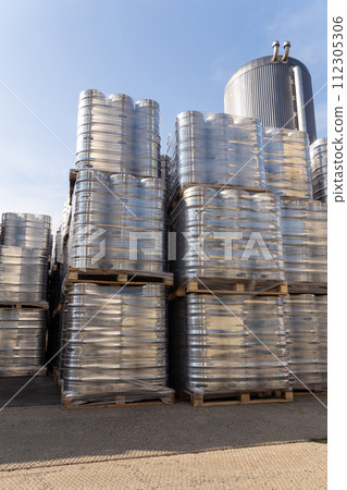 Large amount of aluminium beer kegs stacked on each other with euro palettes and wrapped around with vinyl foil. 112305306