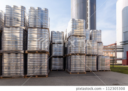 Large amount of aluminium beer kegs stacked on each other with euro palettes and wrapped around with vinyl foil. 112305308