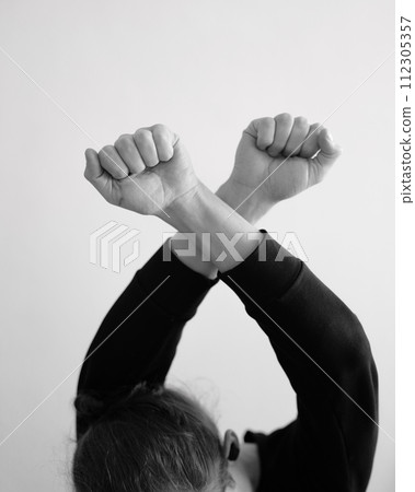 A person holding crossed hands above the head. X symbol using the hands in black and white A person holding crossed hands above the head. X symbol using the hands in black and white 112305357
