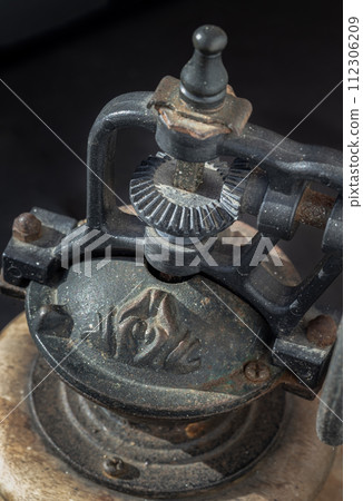 Detail of Antique coffee bean original grinder metal shake wheel with hand crank on dark background. Detail of Antique coffee bean original grinder metal shake wheel with hand crank on dark background. 112306209