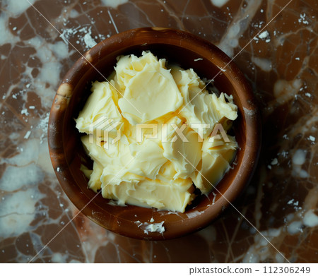 Closeup view showcases a yellow texture of creamy butter or margarine in a wooden bowl 112306249