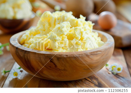 Closeup view showcases a yellow texture of creamy butter or margarine in a wooden bowl 112306255