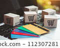 Shopping online. Credit card and cardboard box with a shopping cart logo on laptop keyboard. Shopping service on The online web. offers home delivery 112307281