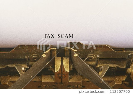 Closeup on vintage typewriter. Front focus on letters making TAX SCAM text. Business concept image with retro office tool Closeup on vintage typewriter. Front focus on letters making TAX SCAM text. Business concept image with retro office tool 112307700