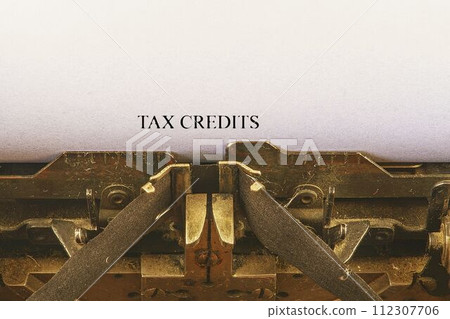 Closeup on vintage typewriter. Front focus on letters making TAX CREDITS text. Business concept image with retro office tool Closeup on vintage typewriter. Front focus on letters making TAX CREDITS text. Business concept image with retro office tool 112307706
