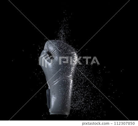 Grey Boxing glove hit sand and explode. Gray Boxer glove impact silicon black sand splash as exercise training. Black background isolated 112307850