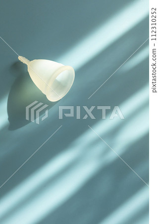 Eco Silicone Reusable Menstrual Cup Isolated on Blue Background with Copy Space for Text. Flatly. Absorbing Period Flow. Personal Intimate Hygiene. Woman Menstruation Cycle, Gynecology. Vertical Eco Silicone Reusable Menstrual Cup Isolated on Blue Background with Copy Space for Text. Flatly. Absorbing Period Flow. Personal Intimate Hygiene. Woman Menstruation Cycle, Gynecology. Vertical 112310252