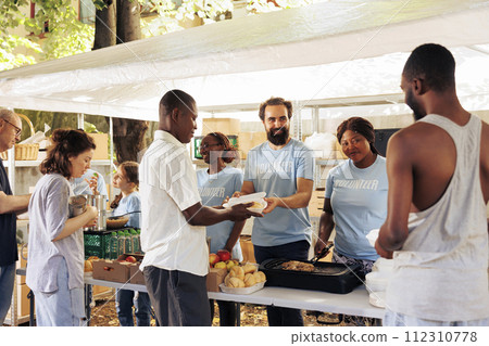 Assisting the needy, compassionate volunteers distribute essential items at a homeless center. Non-porift hunger relief team provide free food, support, and donations to the poor and less privileged. 112310778