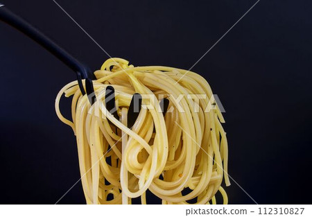 Cooked spaghetti on spaghetti spoon. Spaghetti on black background. Close-up. Dark food photo. Copy space 112310827
