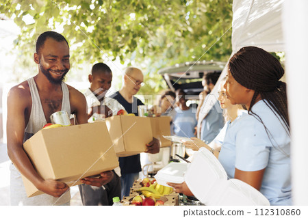 Smiles and teamwork shine through as volunteers provide assistance to the homeless and individuals facing poverty. Image captures the heartwarming impact of charity and food drives. 112310860