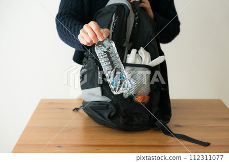 A woman putting a plastic bottle into her disaster prevention backpack 112311077