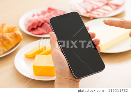 A woman with fat-rich foods and a smartphone 112311782