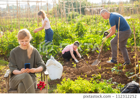 Woman relaxing in chair on garden and browsing in phone Woman relaxing in chair on garden and browsing in phone 112312252