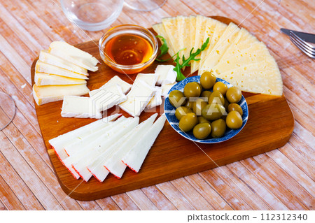 Sliced cheese served with honey and olives 112312340