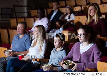 Teenage girl with parents and preteen brother watching movie in cinema Teenage girl with parents and preteen brother watching movie in cinema 112312366