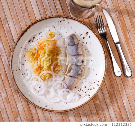 Slices herring fish with pickled cabbage, served on plate Slices herring fish with pickled cabbage, served on plate 112312385
