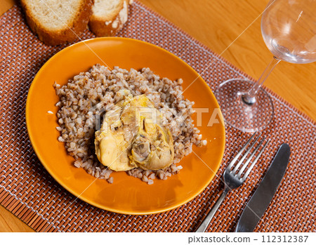 Boiled buckwheat in bowl with chicken thighs. Dinner table, healthy food concept Boiled buckwheat in bowl with chicken thighs. Dinner table, healthy food concept 112312387
