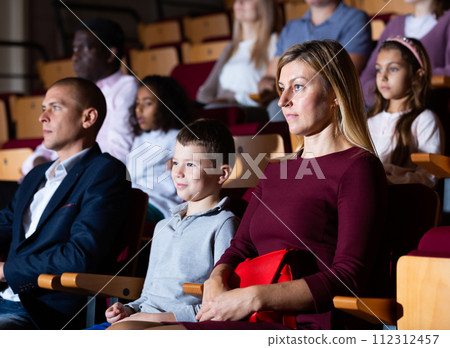 parents with children sitting at premiere in theatrical auditorium 112312457