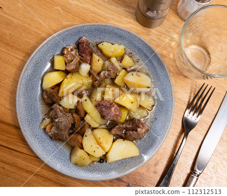 There is portion of stewed veal with vegetables in deep plate 112312513