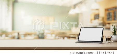 A digital tablet and a presentation space on a wooden table in a cosy, contemporary coffee shop. A digital tablet and a presentation space on a wooden table in a cosy, contemporary coffee shop. 112312624