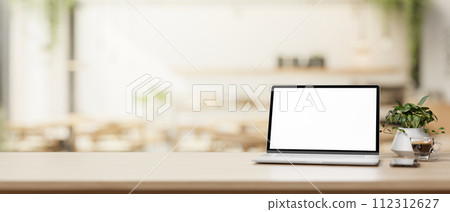 A laptop computer and a presentation space on a wooden table in a cosy, contemporary coffee shop. A laptop computer and a presentation space on a wooden table in a cosy, contemporary coffee shop. 112312627