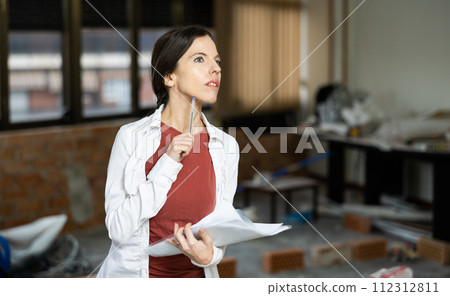 Interested brunette making notes while planning home renovation 112312811