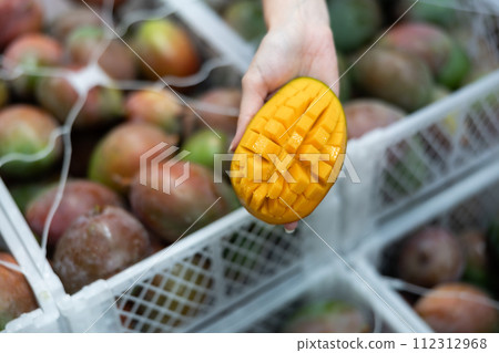 Fresh sliced mango on hand, blurred boxes with fruits on background 112312968