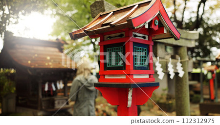 Japan, nature and wooden lantern in Kyoto with trees, tourist and woman with torii gate. Architecture, japanese culture and shinto shrine in woods with sculpture, religion memorial and monument Japan, nature and wooden lantern in Kyoto with trees, tourist and woman with torii gate. Architecture, japanese culture and shinto shrine in woods with sculpture, religion memorial and monument 112312975