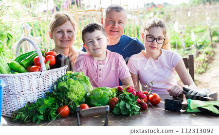 Family discusses the harvest of vegetables at the table of the village house 112313092