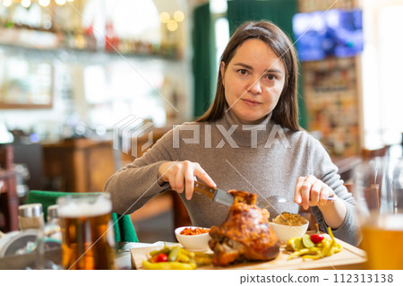 Positive brunette having lunch in cafe with roasted ham hock and beer 112313138