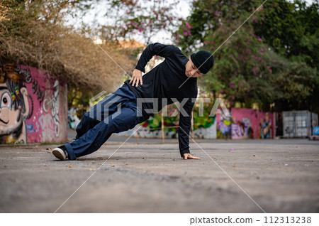 A cool and talented Asian male b-boy dancer or breakdancer is dancing on the street. A cool and talented Asian male b-boy dancer or breakdancer is dancing on the street. 112313238