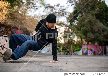 A cool, stylish Asian male hiphop dancer is dancing on the street in the city, practicing b-boy. A cool, stylish Asian male hiphop dancer is dancing on the street in the city, practicing b-boy. 112313254