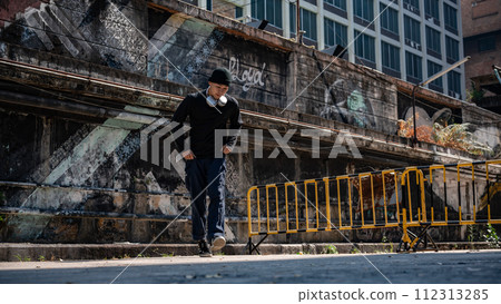 A cool, hipster Asian man is enjoying with the rhythm and dancing hiphop on the street. 112313285