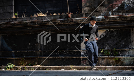 A cool, active Asian male hiphop dancer in fashionable clothes is breakdancing on the street. A cool, active Asian male hiphop dancer in fashionable clothes is breakdancing on the street. 112313305
