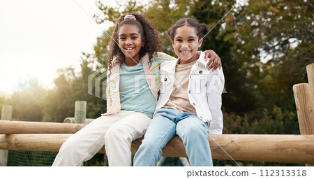 Friends, happy and children hug in park on jungle gym for bonding, childhood and having fun on playground. Friendship, outdoors and portrait of young girls embrace for playing, freedom and adventure 112313318