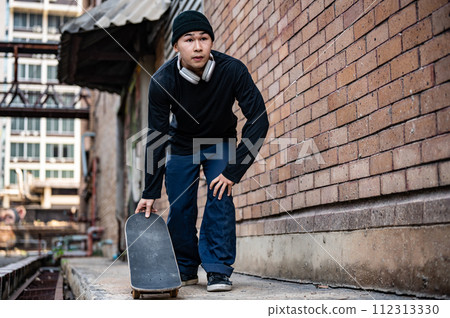 A stylish, hipster Asian male skater is practicing skateboard, skateboarding on the city street. 112313330