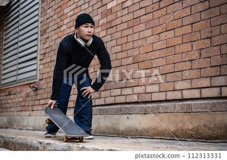 A stylish, hipster Asian male skater is practicing skateboard, skateboarding on the city street. 112313331