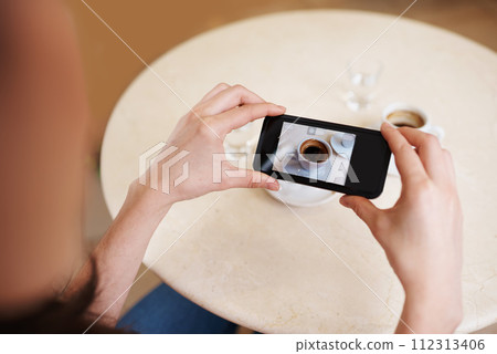Hands, smartphone screen and top view photography of coffee, tea or espresso for social media, content or blogging. Closeup, person and cellphone with hot beverage cup at restaurant, cafe and table 112313406