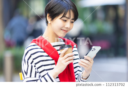 A young woman operating a smartphone 112313702