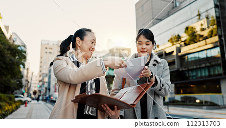 Documents, discussion and Japanese business people in city for morning commute, travel and walking. Collaboration, corporate team and women with paperwork for meeting, talking and project in Tokyo 112313703