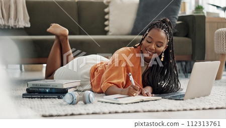 Laptop, happy and woman writing notes on the floor in the living room of modern apartment. Technology, smile and young African female university student studying on a computer in the lounge at home. 112313761