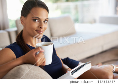 Portrait, drinking coffee and woman reading book in home to relax, education or learning at breakfast in the morning. Novel, tea cup or face of person with espresso, latte and study on sofa in lounge 112313817