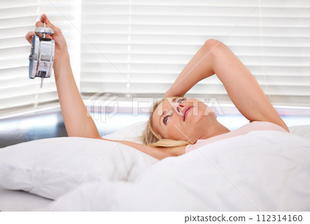 Woman, alarm clock and late for waking up in bed, tired and sleepless or fatigue at home. Female person, exhausted and pressing or hit snooze in apartment, frustrated and depression or lazy and sad 112314160