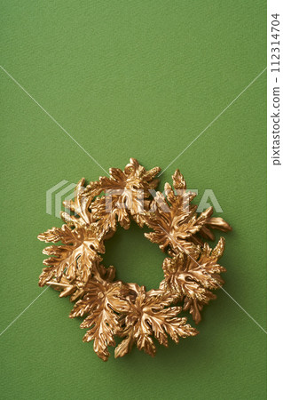 綠色背景上放置的金色聖誕花環 112314704