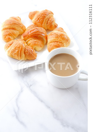Breakfast table with freshly baked croissants and freshly brewed cafe au lait Breakfast table with freshly baked croissants and freshly brewed cafe au lait 112316111