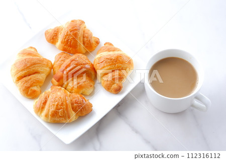 Breakfast table with freshly baked croissants and freshly brewed cafe au lait Breakfast table with freshly baked croissants and freshly brewed cafe au lait 112316112