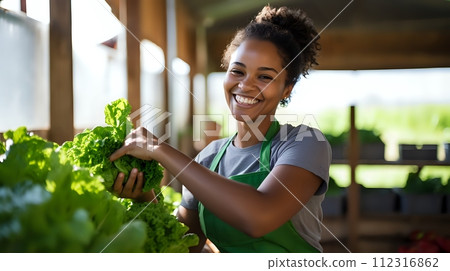 A young woman wearing a green apron is harvesting lettuce in a g A young woman wearing a green apron is harvesting lettuce in a g 112316862